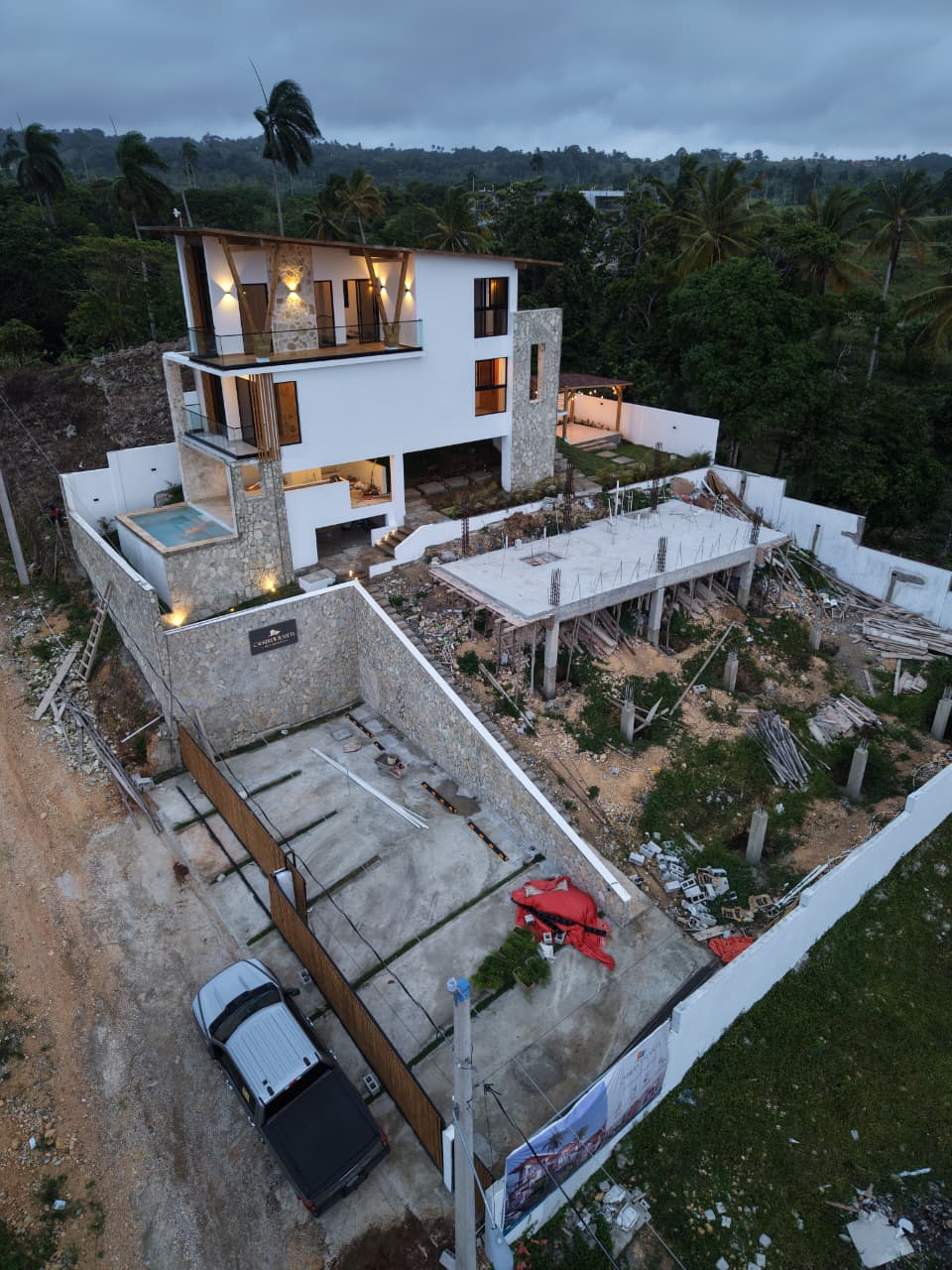 Exterior de la villa al atardecer con el letrero del proyecto